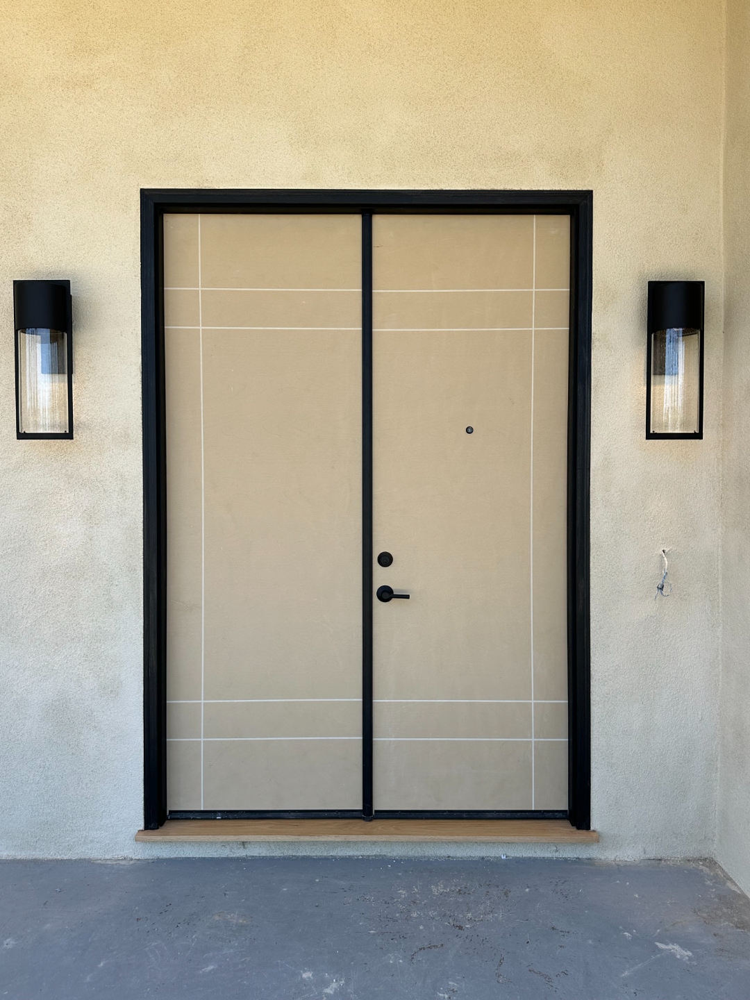 Modern double entry door with black frame and matching wall sconces