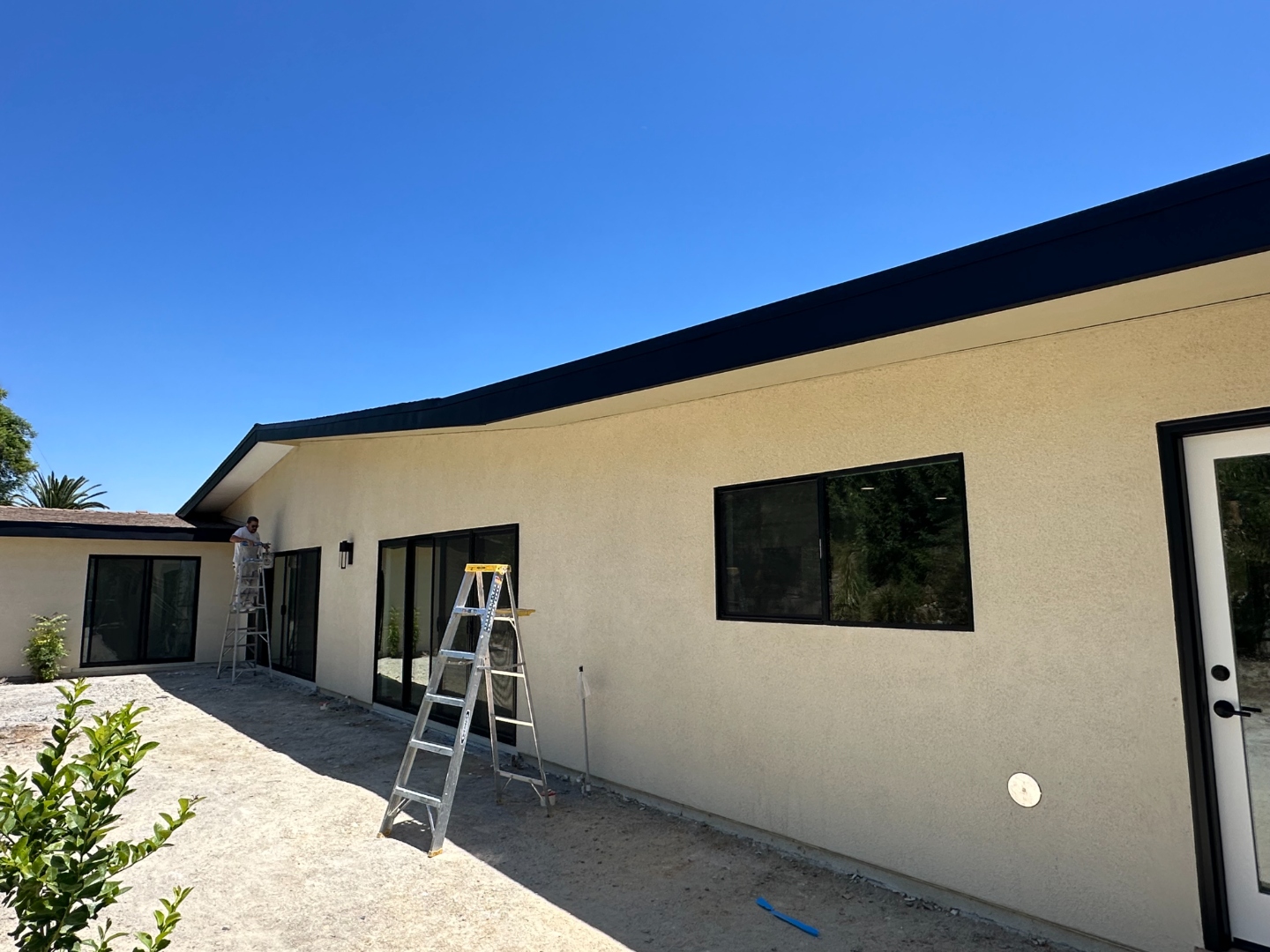 Rear exterior of Canzonet remodel with new stucco, sliding doors and landscaping