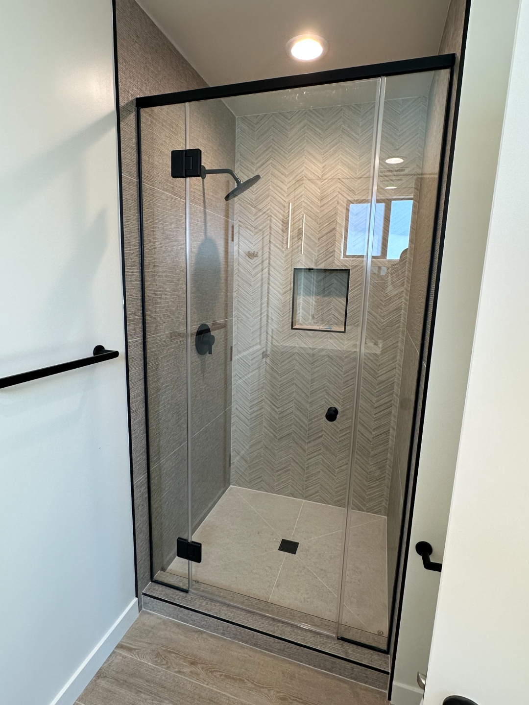 Guest shower with herringbone tile and frameless glass enclosure