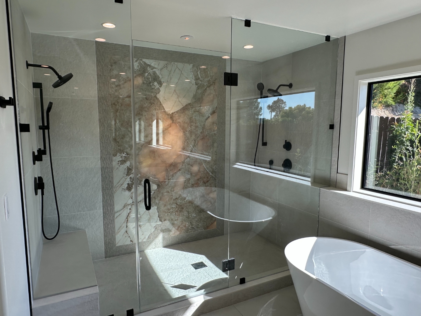 Master shower with dramatic stone slab feature wall and dual rain heads