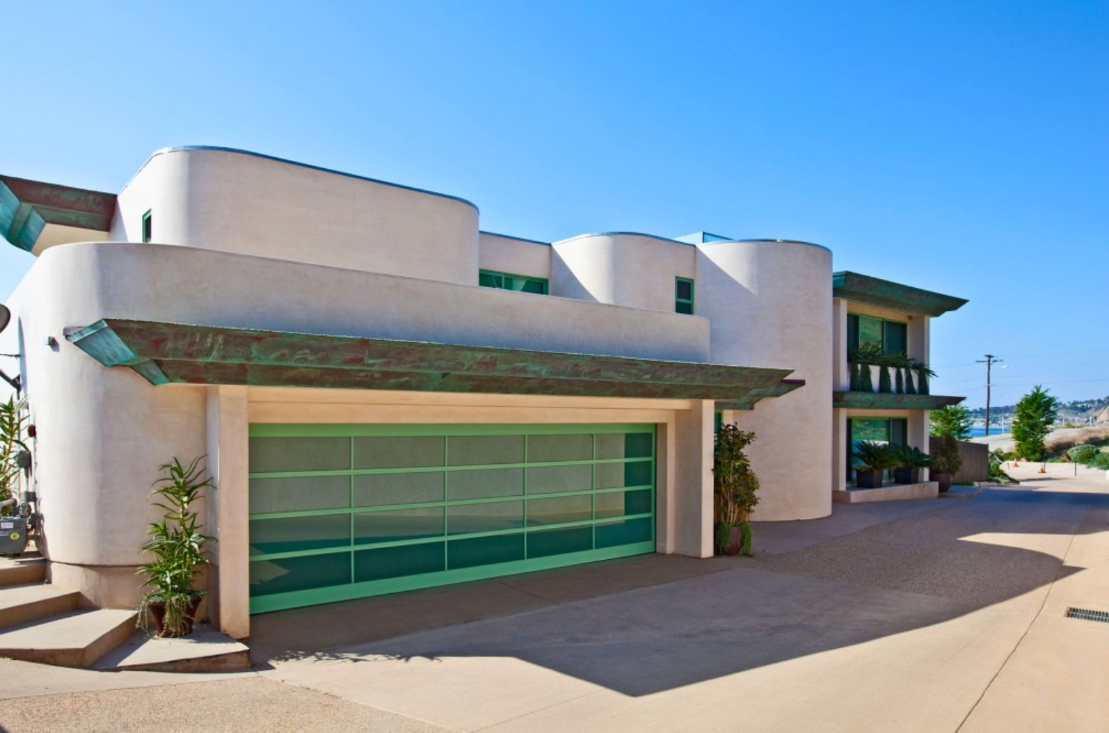 Street-facing facade with curved forms and green glass garage