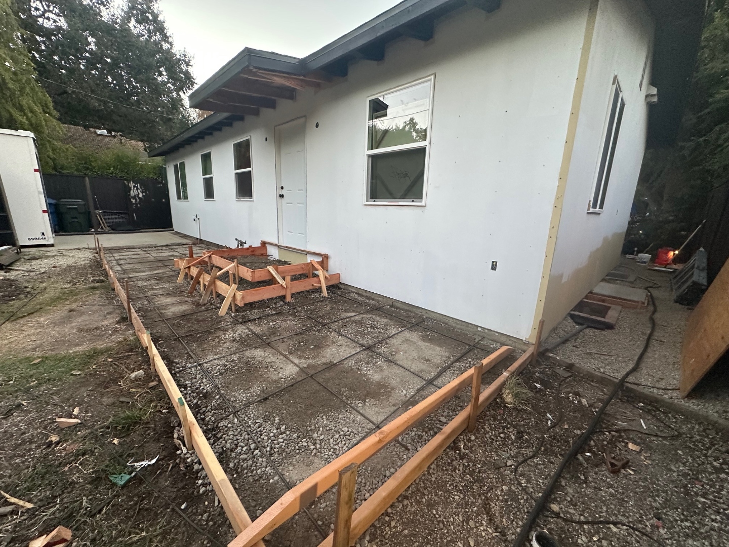 New stucco rear exterior with concrete flatwork rebar grid and formwork in progress